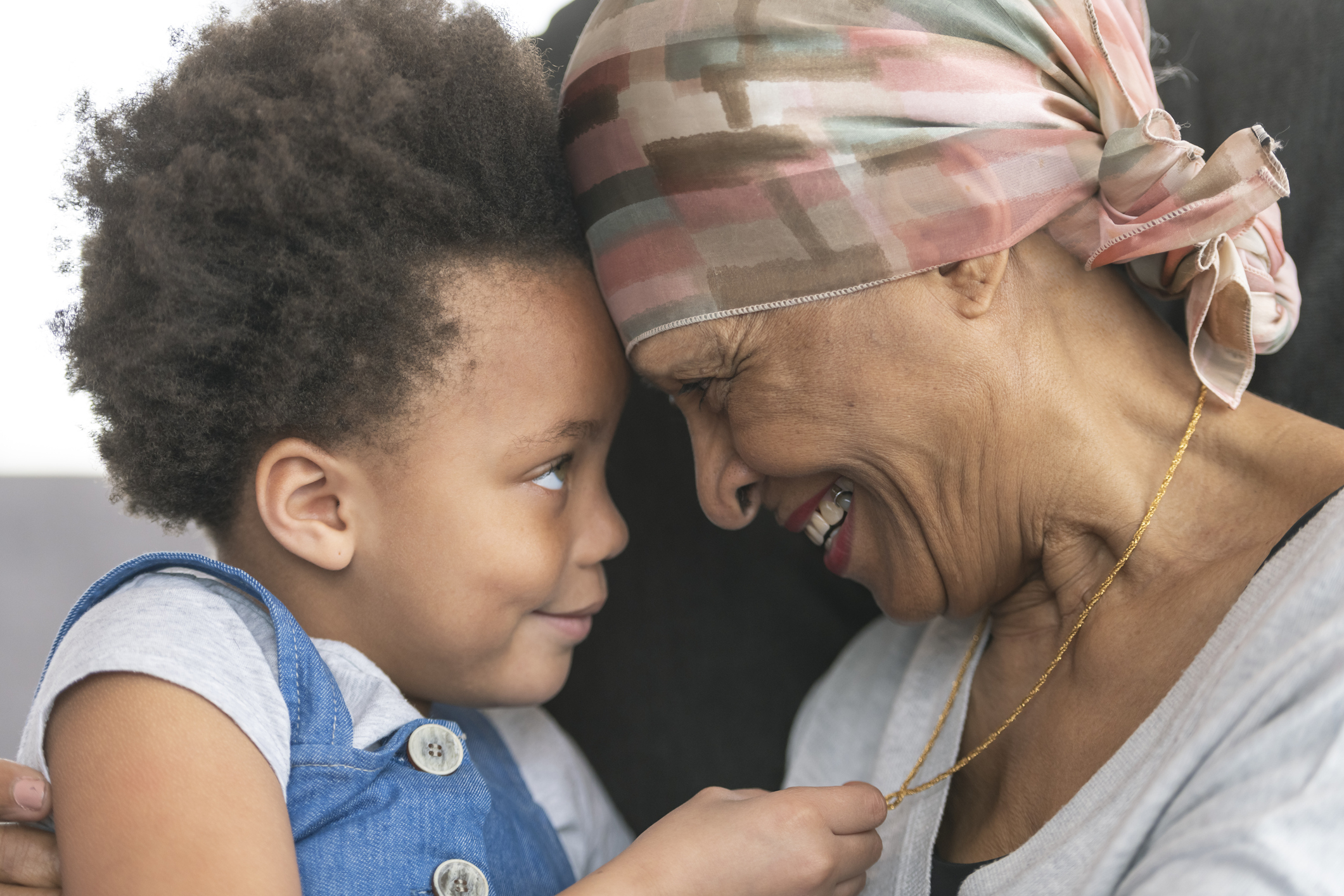 Senior woman with cancer lovingly holds granddaughter